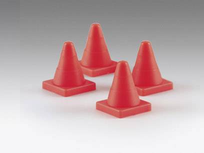 Quatre cônes de signalisation rouges sont disposés symétriquement sur une surface grise, probablement pour délimiter une zone ou signaler un danger.