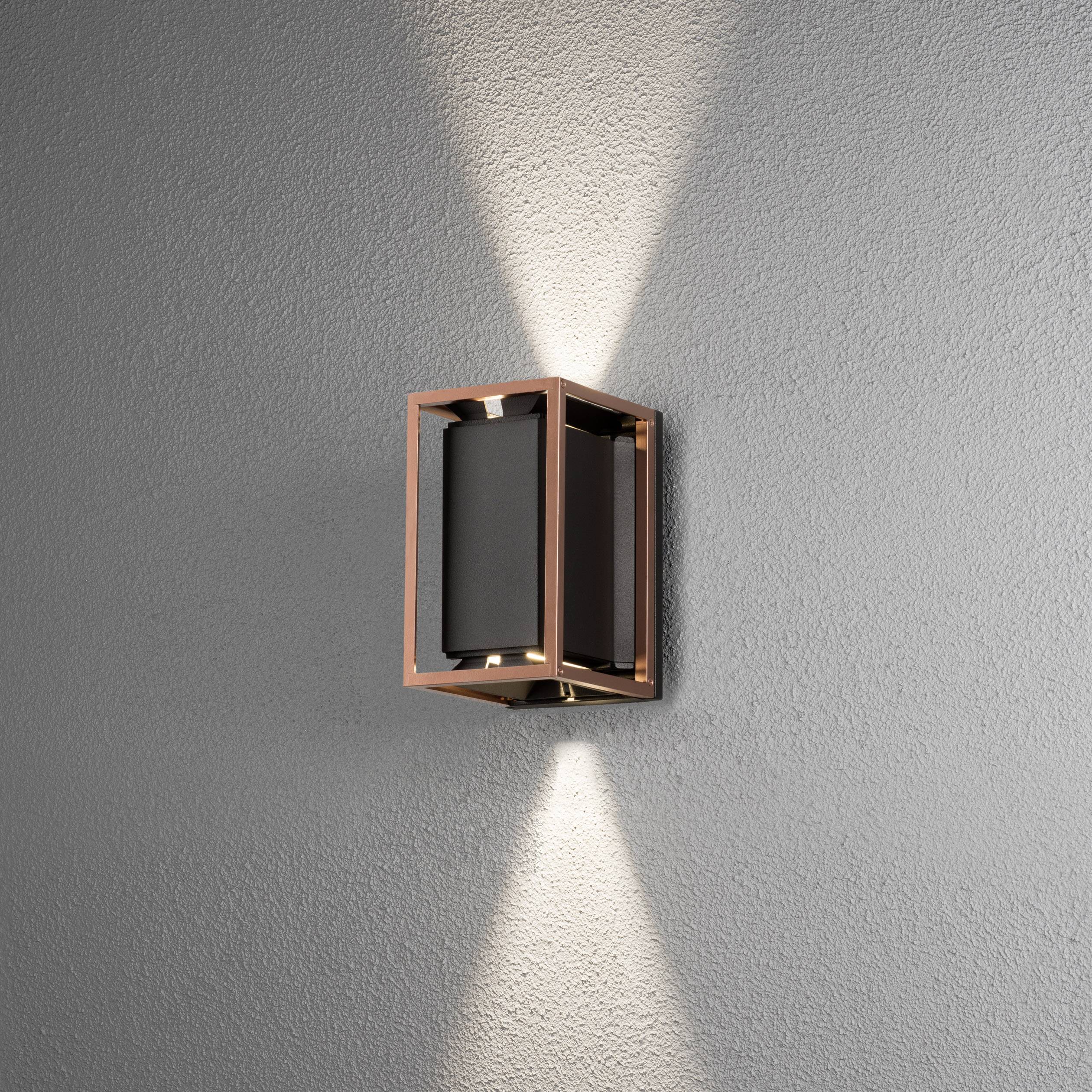 Applique murale au design moderne et rectangulaire, projetant des rayons lumineux vers le haut et le bas sur un mur gris.