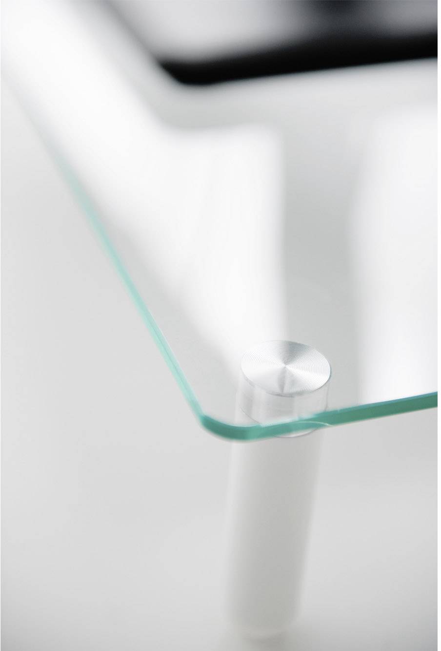 Une table en verre avec un coin arrondi, photographiée sur un fond blanc. Design minimaliste, ambiance moderne.