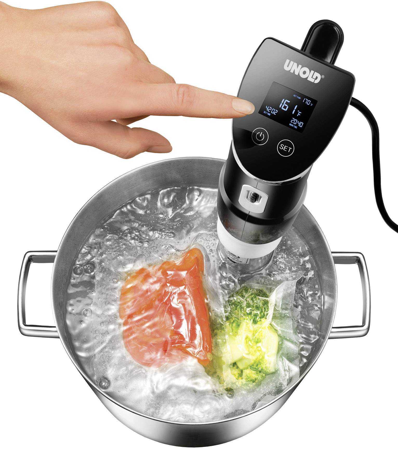 Une main manipule un stick sous-vide suspendu dans une casserole d'eau bouillante. Dans l'eau, des aliments sous vide cuisent lentement.