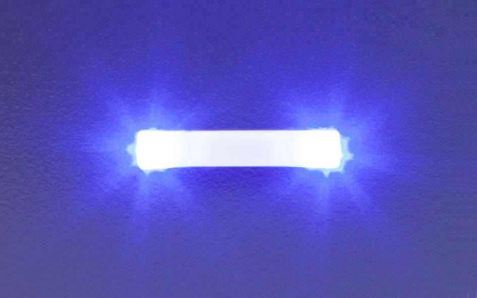 Une barre lumineuse bleue brille sur un fond sombre. La lumière rayonne uniformément vers l'extérieur et crée un effet de halo.