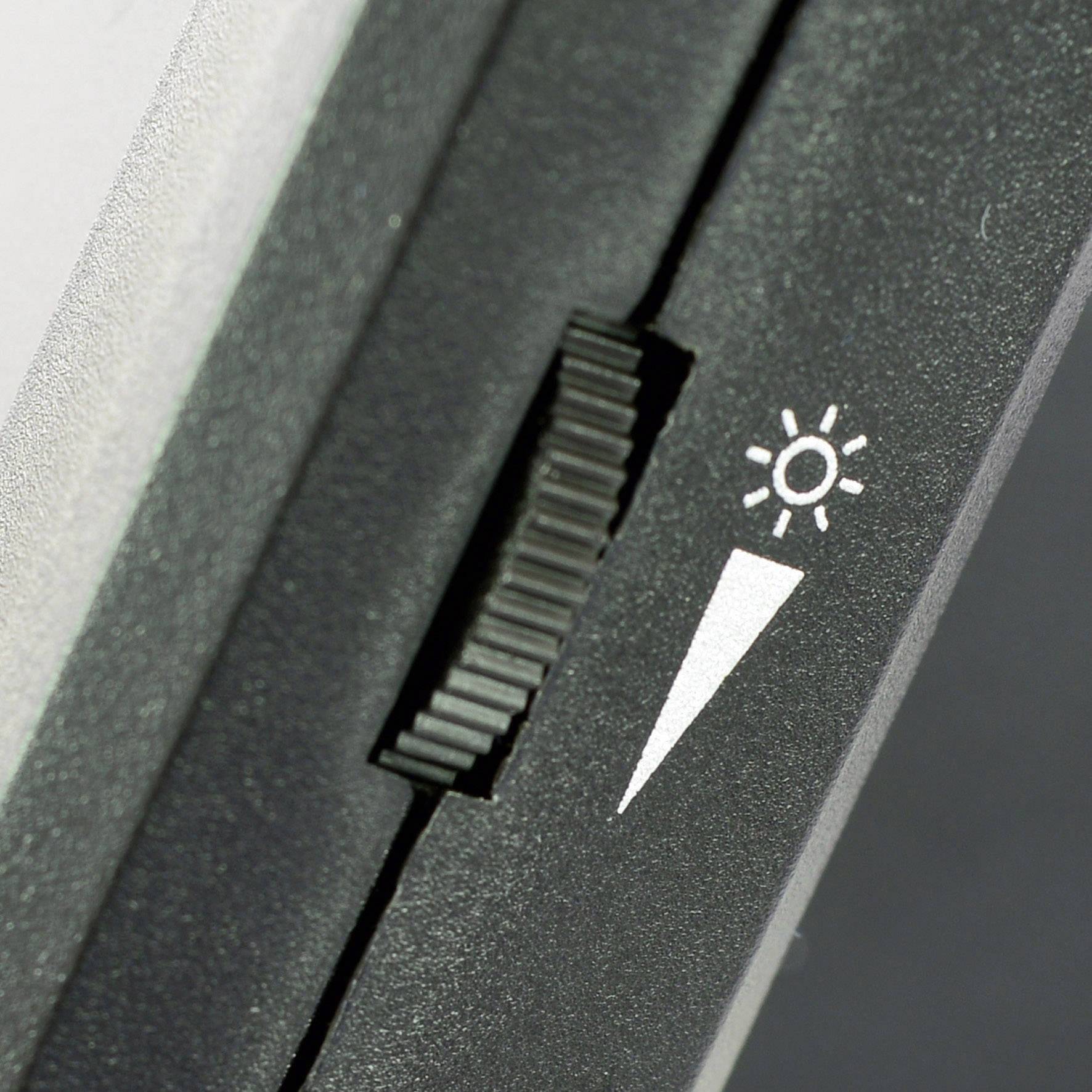 Un gros plan d'un bouton de réglage avec un symbole de soleil, probablement utilisé pour ajuster la luminosité.