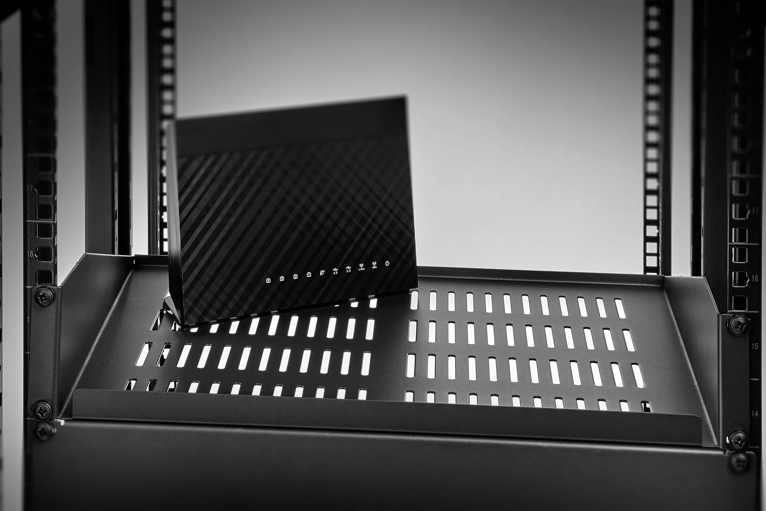 Un modem noir est placé sur une étagère ventilée dans une armoire serveur. Le modem présente des lignes diagonales et est positionné de manière centrale.