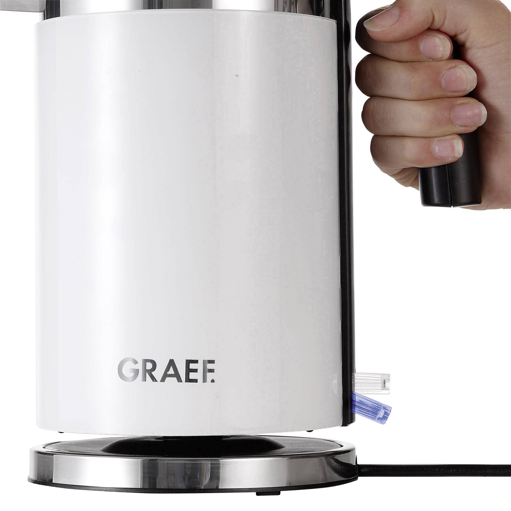 Une main tient la poignée d'une bouilloire électrique sur sa base. La bouilloire est en métal avec la marque 'Graef'.