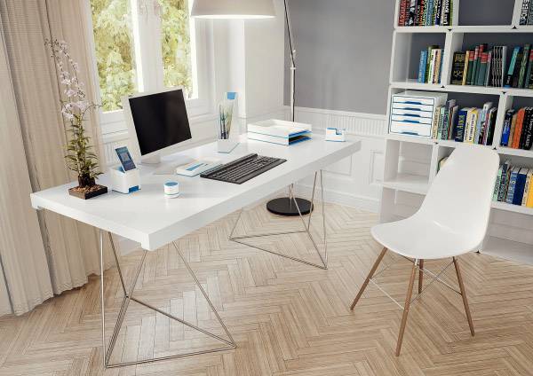 Bureau moderne avec ordinateur, clavier et articles de bureau. Chaise blanche et bibliothèque en arrière-plan, fenêtre donnant sur un espace verdoyant.