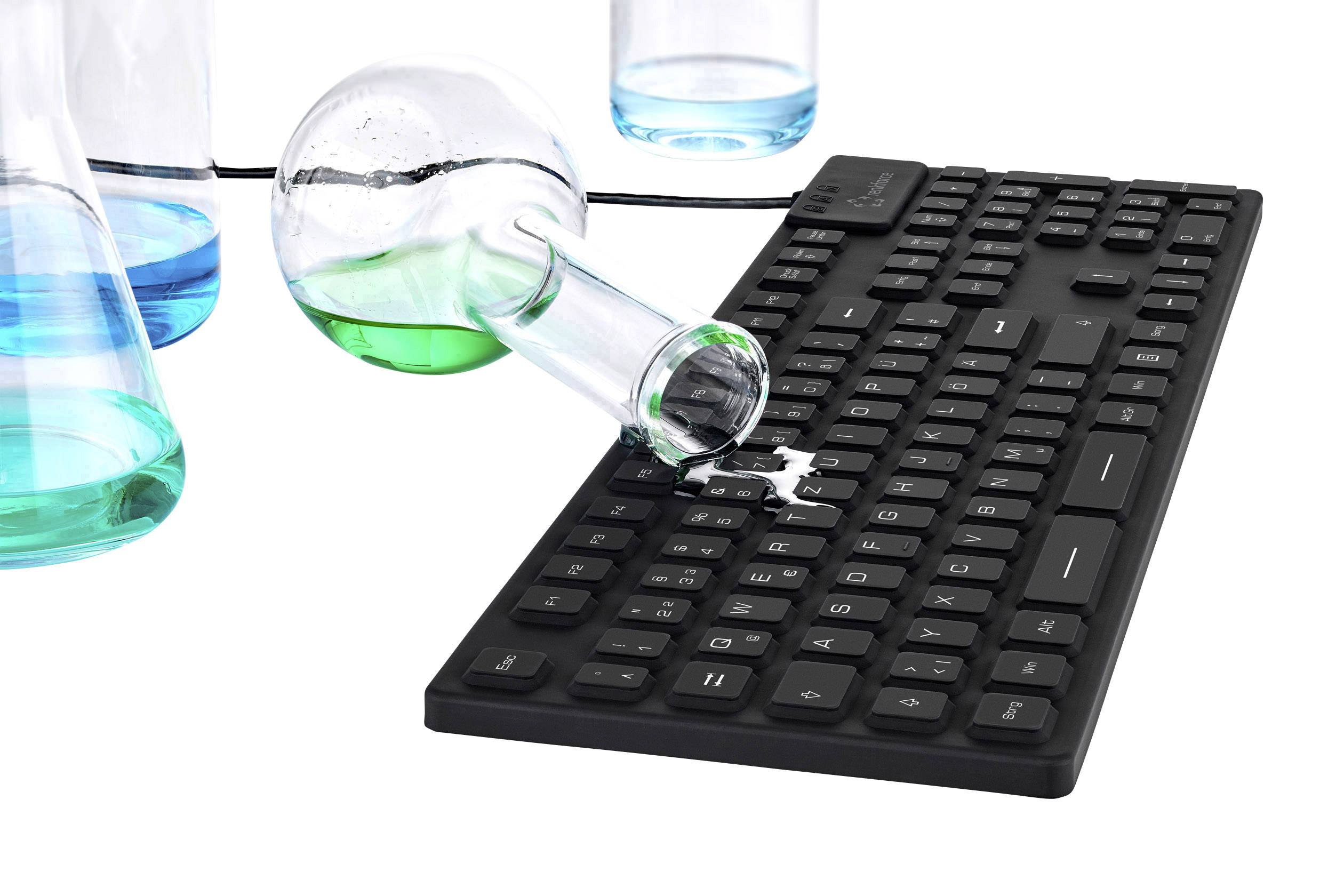 Un clavier noir sur lequel une solution bleu-vert est renversée à partir d'un tube à essais incliné. À l'arrière-plan, d'autres verres de laboratoire sont visibles.