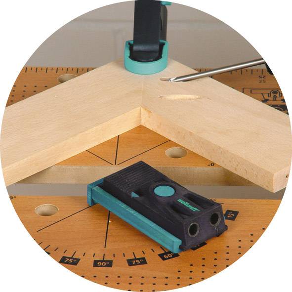 Un morceau de bois est fixé à une table en bois à l'aide d'un connecteur d'angle. Un tournevis est posé à côté.