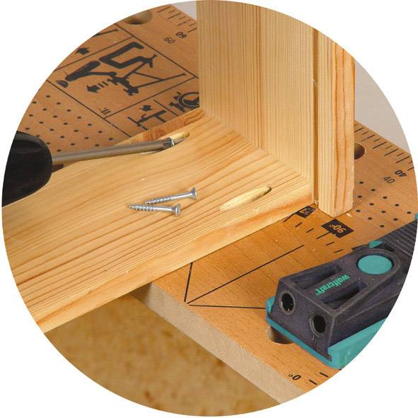 Liaison de bois avec deux vis et trous de perçage correspondants. Un outil de mesure d'angle est posé sur une poutre en bois.