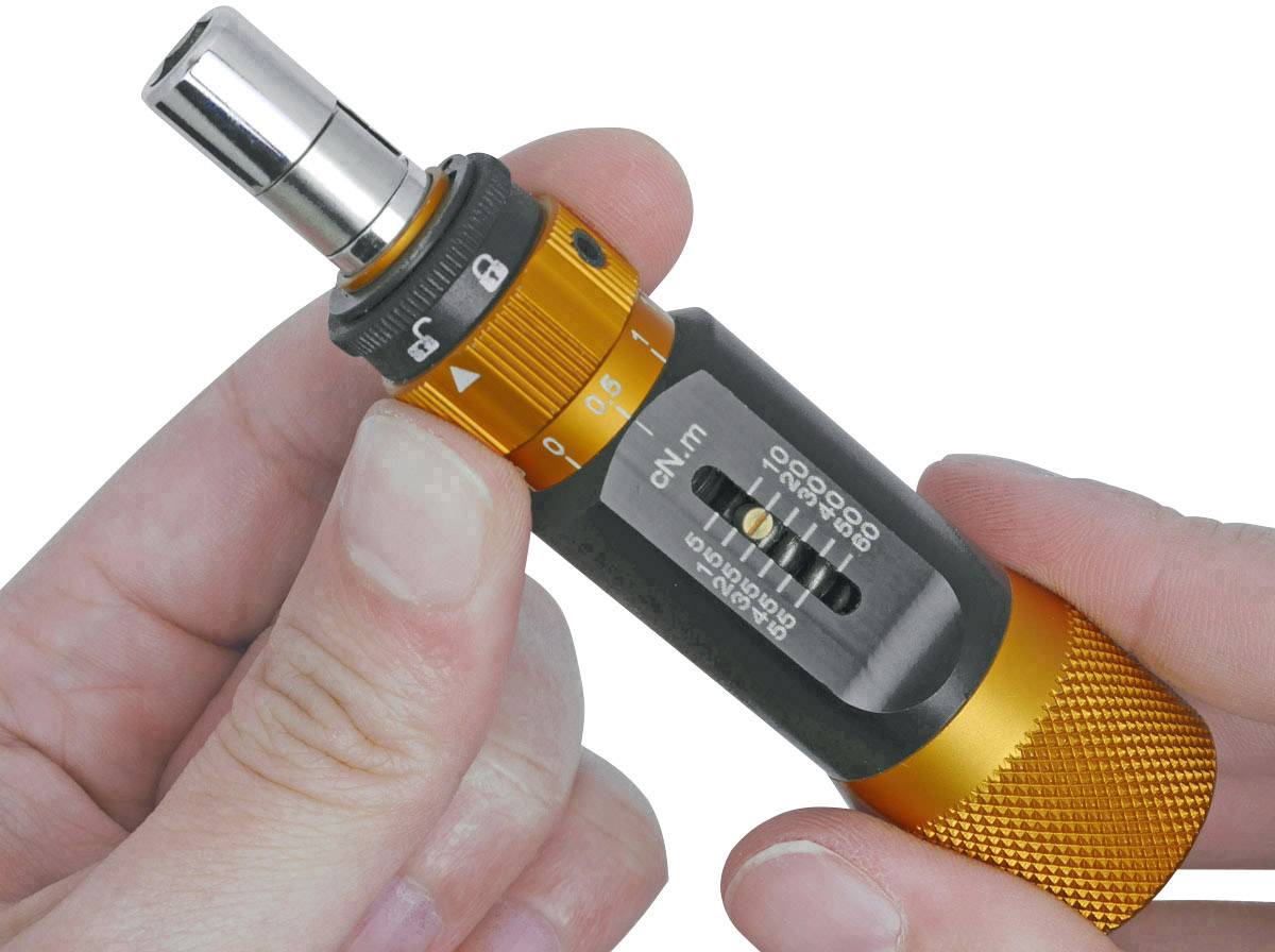 Une personne tient un outil de mesure de couple de couleur orange. Il présente une échelle permettant de régler précisément les valeurs de couple.