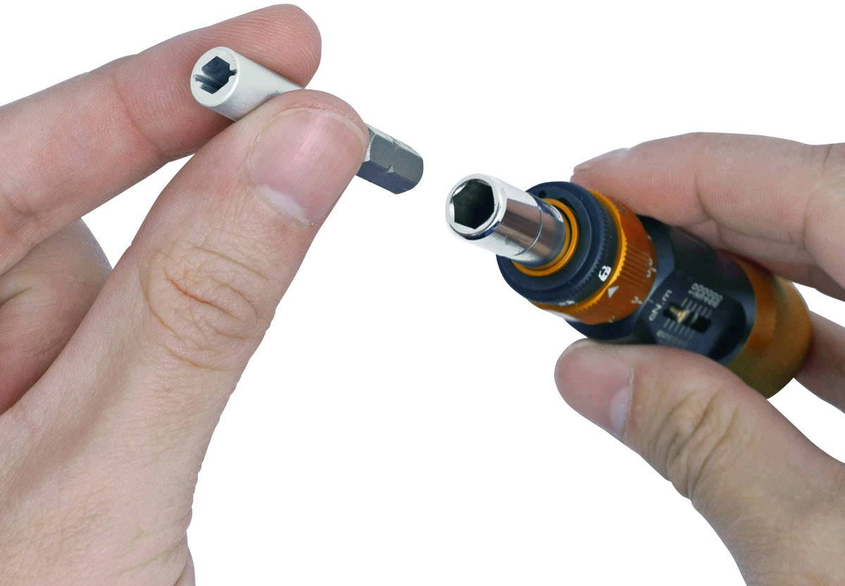 Une main tient un tournevis à embout interchangeable, dont l'embout est en train d'être changé.