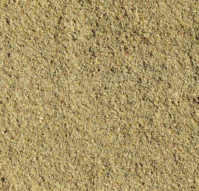 Gros plan sur du sable humide avec une texture granulée fine répartie dans différentes nuances de brun.