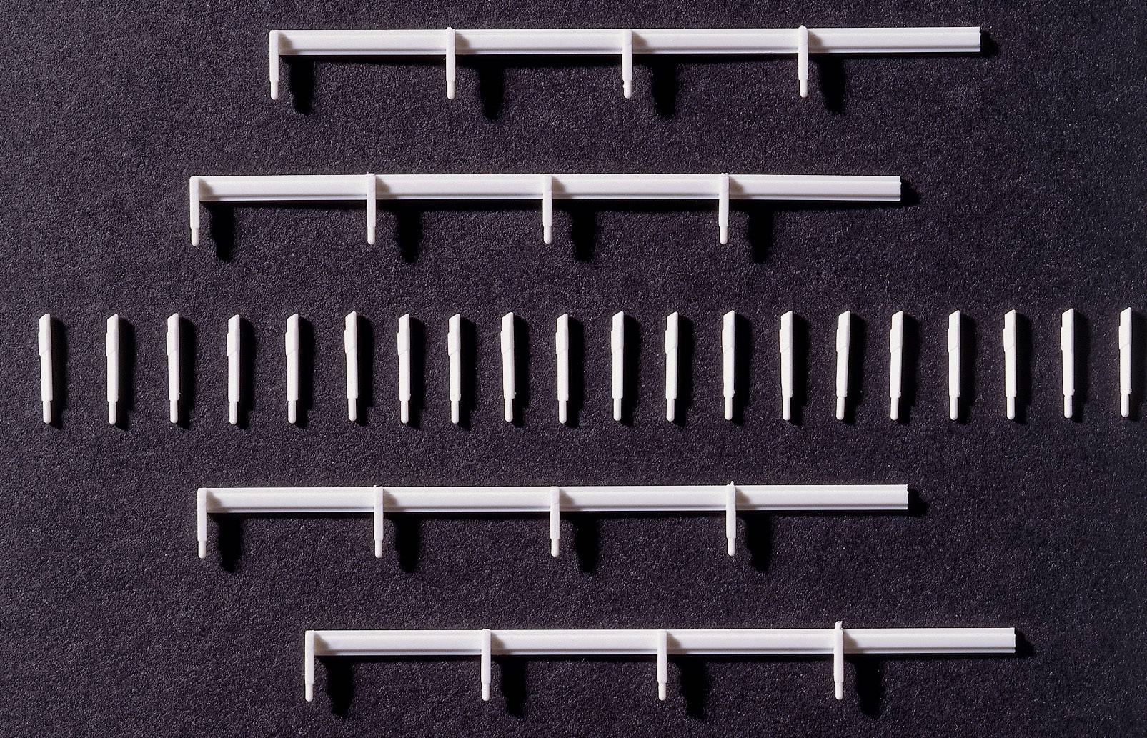 Des clips et chevilles en plastique blanc disposés uniformément sur un fond noir, certains alignés en rangée, d'autres en groupes.