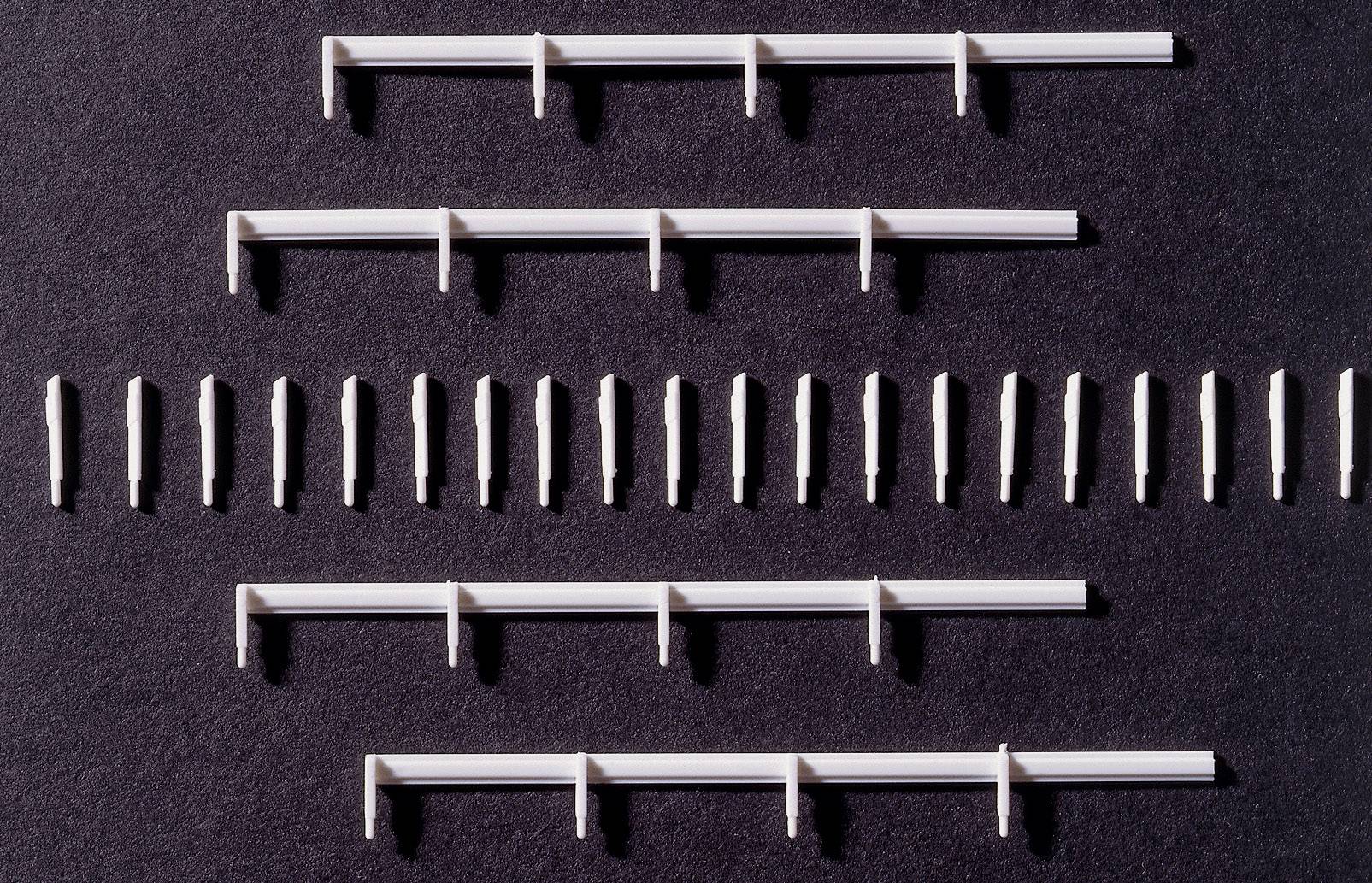 Des composants blancs, allongés, et de petites tiges, disposés symétriquement, sur un fond sombre.