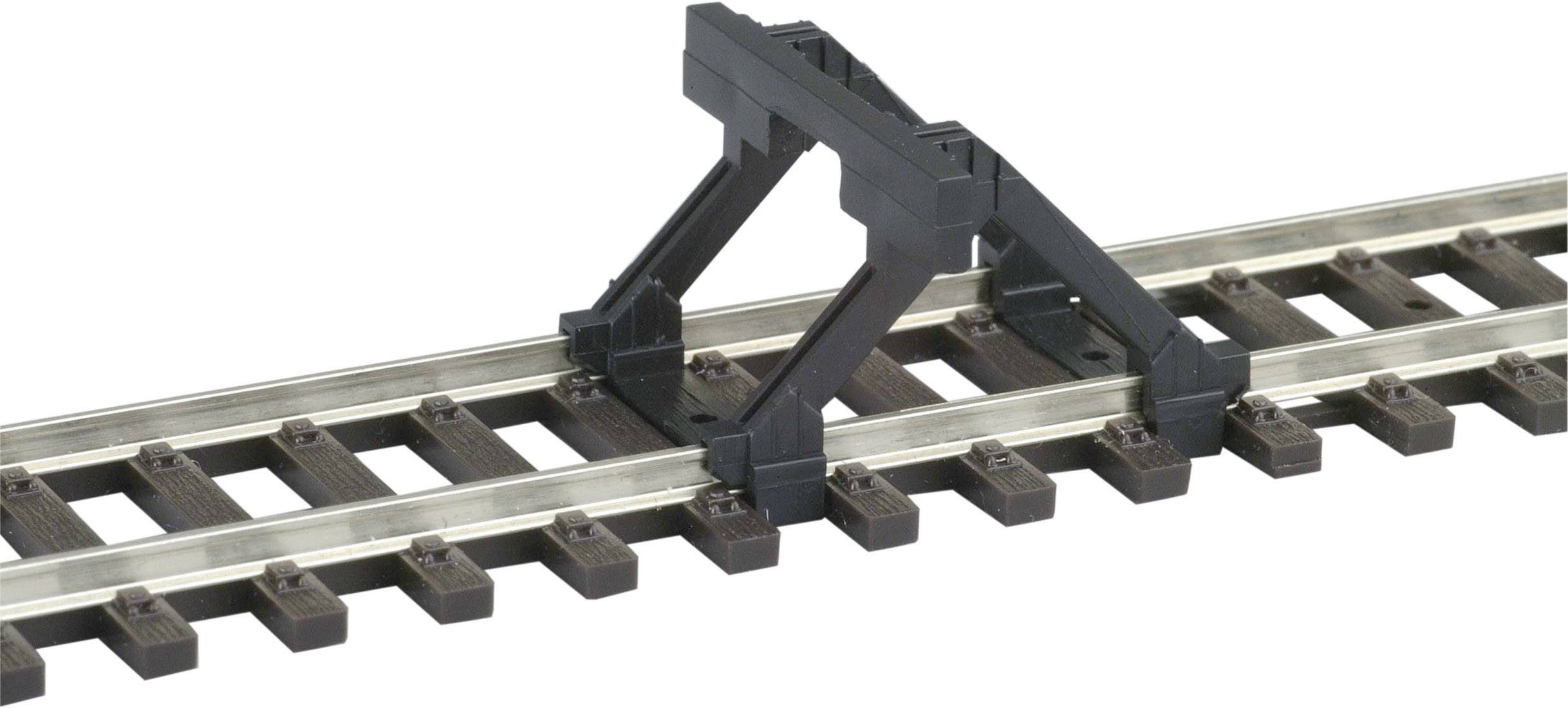 Un butoir en blocs noirs est monté sur un court tronçon de voies de chemin de fer miniature pour arrêter les trains.