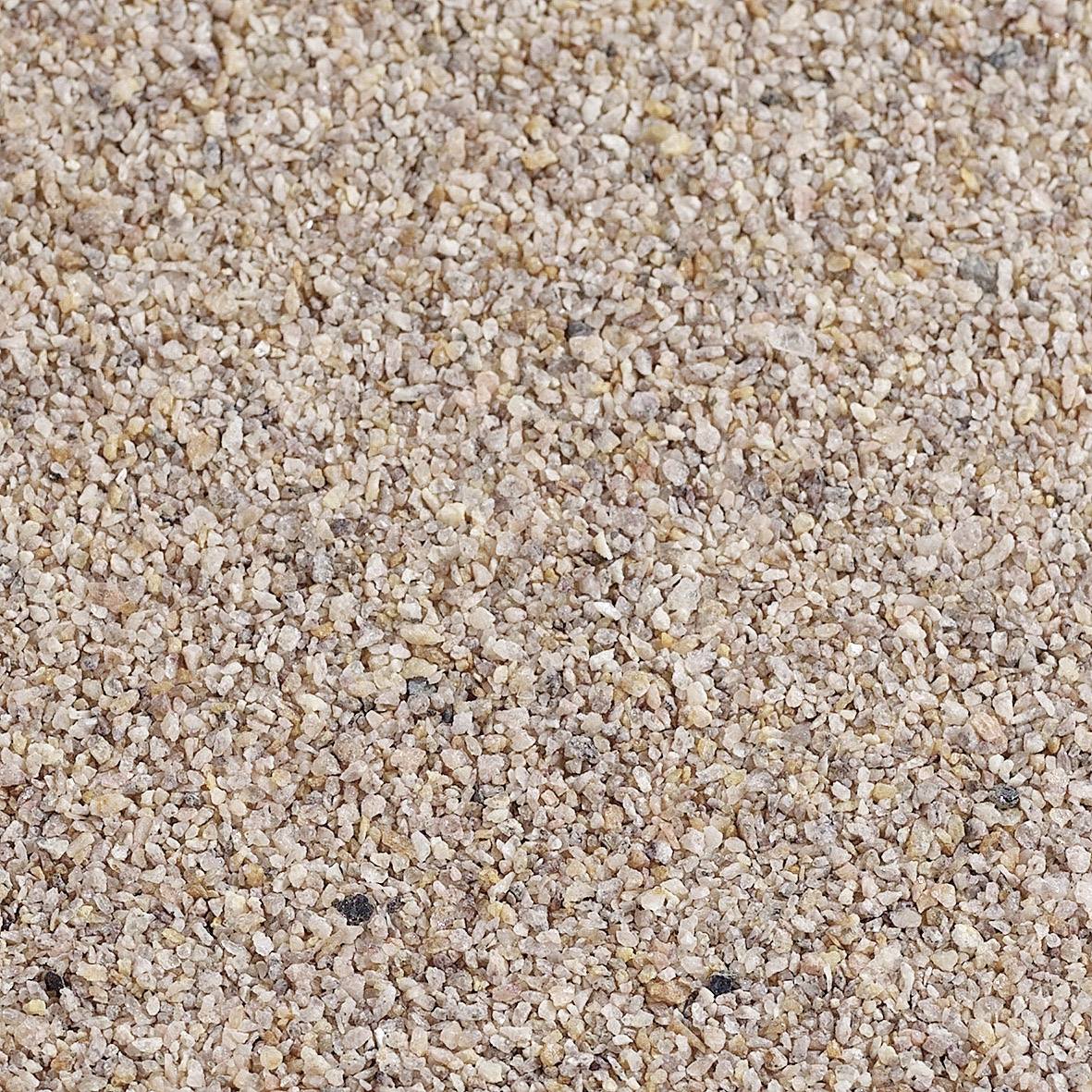 Un gros plan sur une surface couverte de petits grains de sable rugueux dans différentes nuances de brun et de beige, étroitement regroupés.