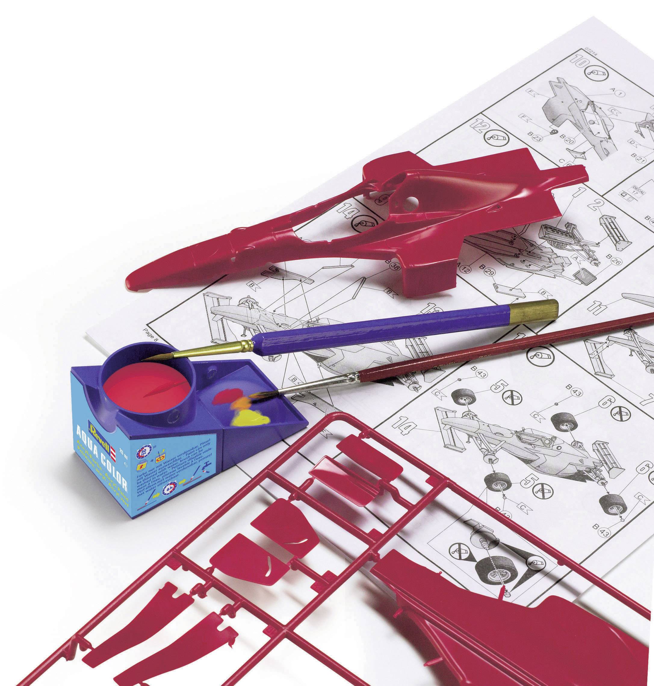 Une maquette présente un bolide de course rouge en pièces détachées, un manuel de montage, de la peinture rouge et un pinceau. Les pièces sont encore sur leur support.