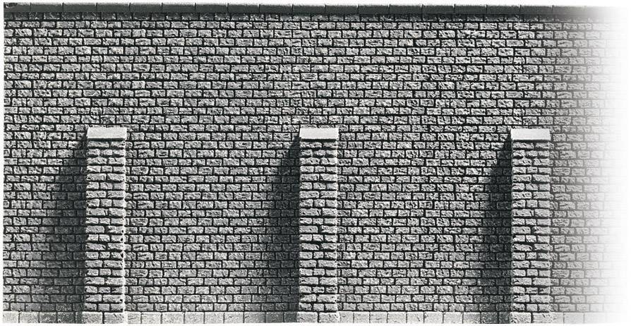'Photo en noir et blanc d'un mur de briques texturé avec trois contreforts verticaux répartis de manière uniforme.'