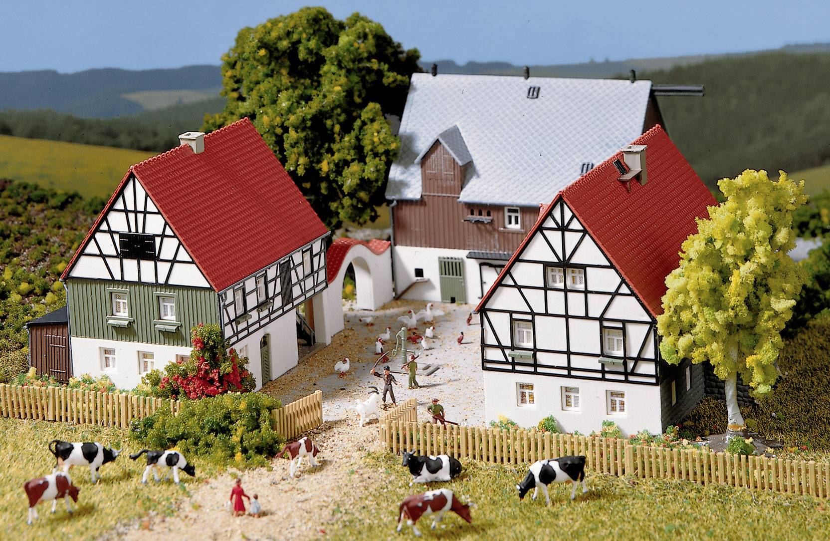 Paysage miniature avec maisons à colombages, ferme et vaches dans un pré. Des personnes et des animaux se déplacent sur le terrain de la ferme.