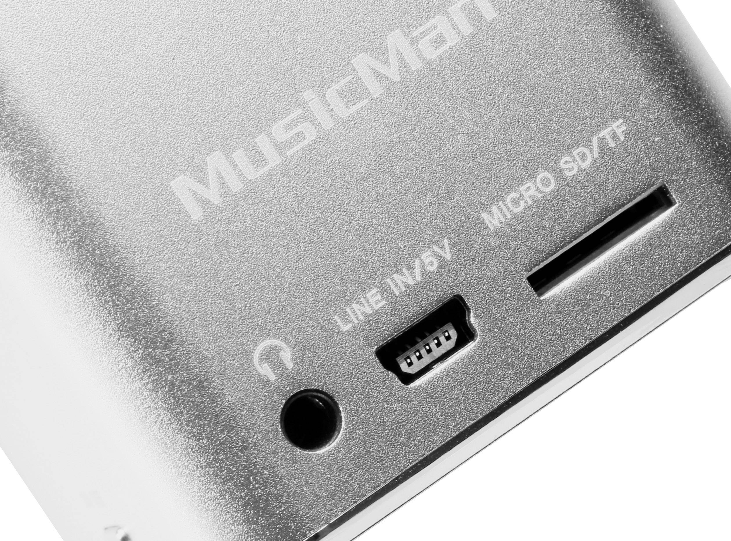 Un appareil électronique argenté portant l'inscription 'MusicMan'. On peut voir une prise pour casque, un port micro-USB et un emplacement pour carte micro-SD.