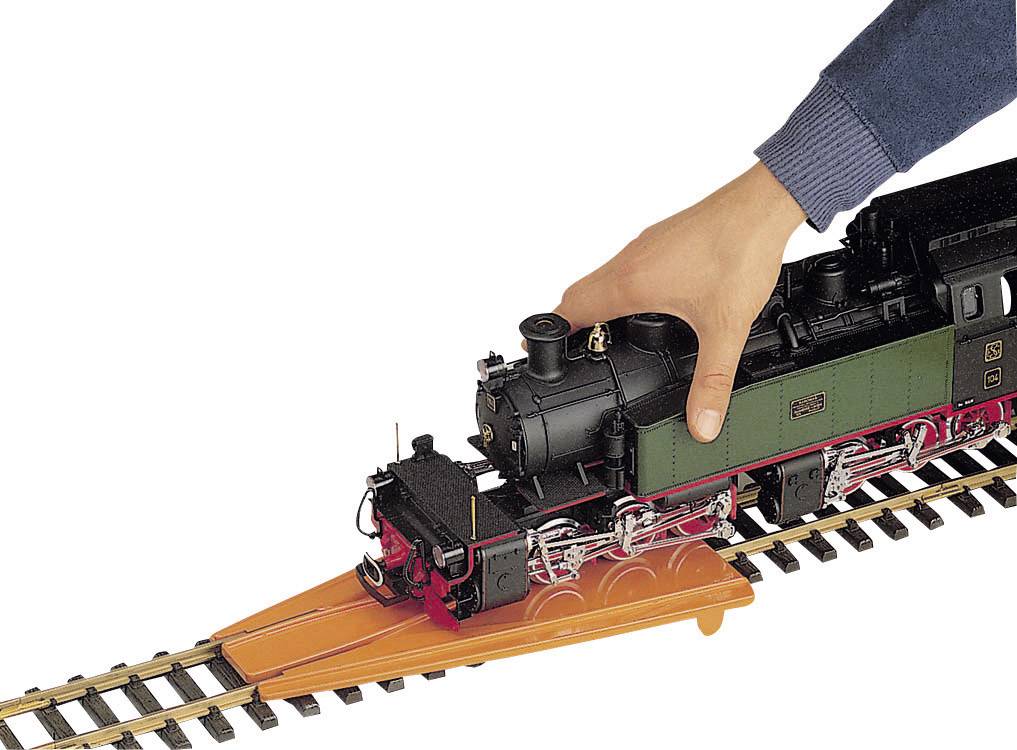 Une main place une locomotive modèle sur des rails à l'aide d'une rampe de voie.