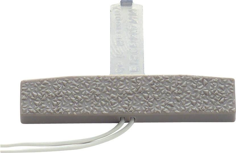 Un appareil gris rectangulaire à surface texturée avec deux câbles en saillie.