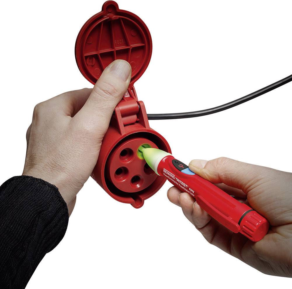 Une personne vérifie une prise électrique rouge à l'aide d'un testeur de tension afin de contrôler la sécurité électrique.