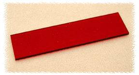 Un objet rectangulaire rouge, posé à plat sur un fond clair.