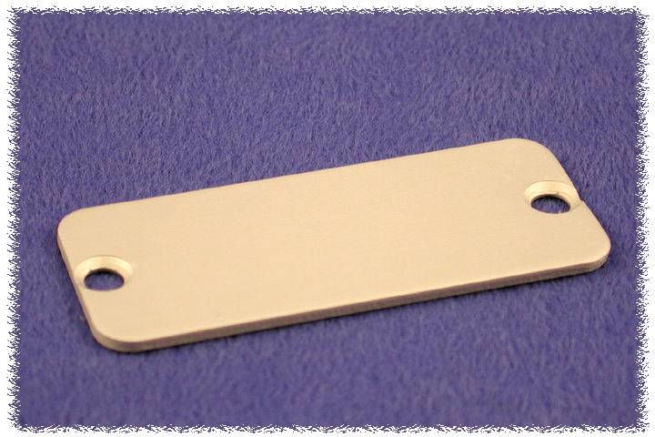 Une plaque métallique rectangulaire avec deux trous à ses extrémités repose sur une surface bleue.