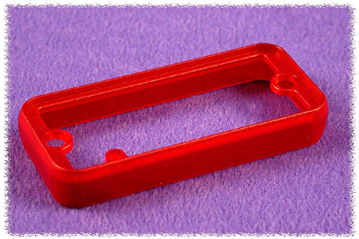 Une pièce en plastique rouge, rectangulaire, avec deux trous, repose sur un fond lilas.