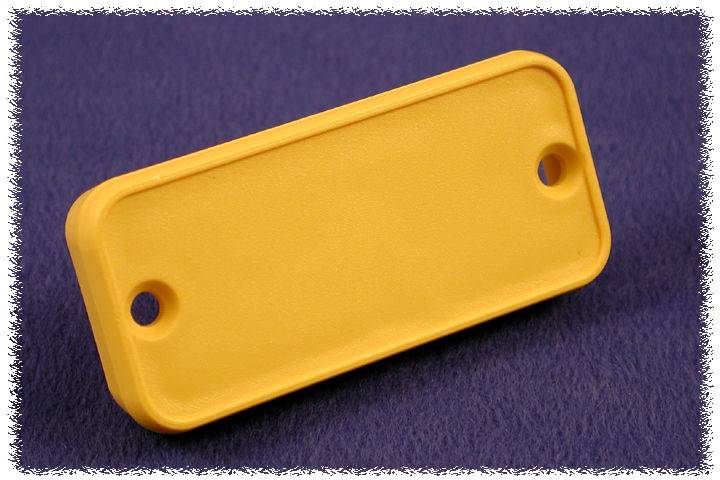 Un morceau rectangulaire jaune en plastique avec deux trous à ses extrémités, reposant sur un fond bleu.