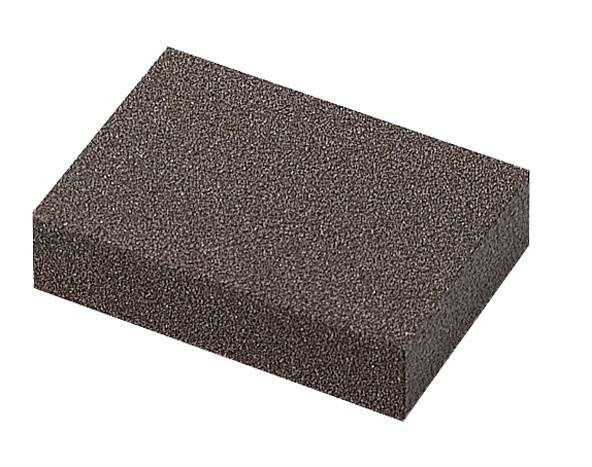 Une éponge de ponçage rectangulaire en mousse gris foncé, posée à plat sur une surface claire. Idéale pour le ponçage manuel.