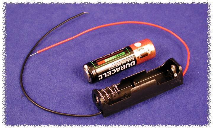 Support de batterie avec une pile Duracell retirée et deux câbles sortants, un rouge et un noir, sur un fond bleu.