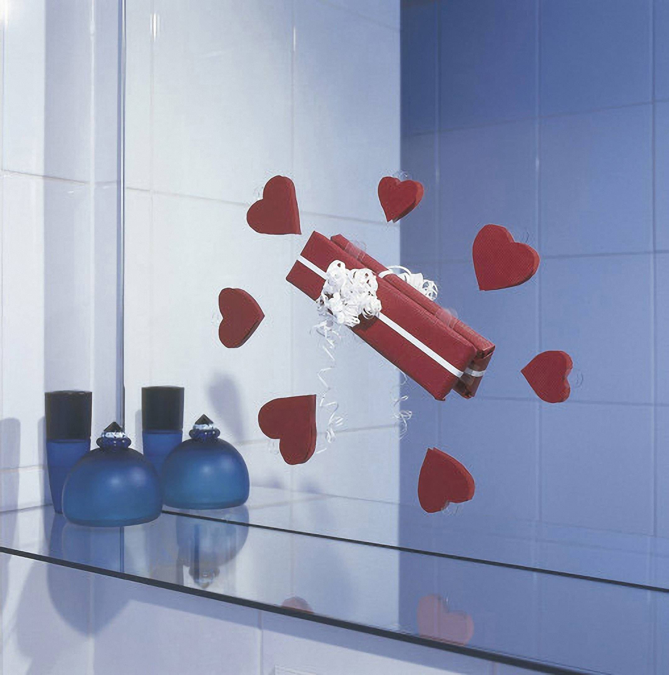 Cadeau rouge orné de rubans blancs, entouré de formes de cœurs, flottant au-dessus d'une surface de verre bleu dans une salle de bain aux carreaux bleus.