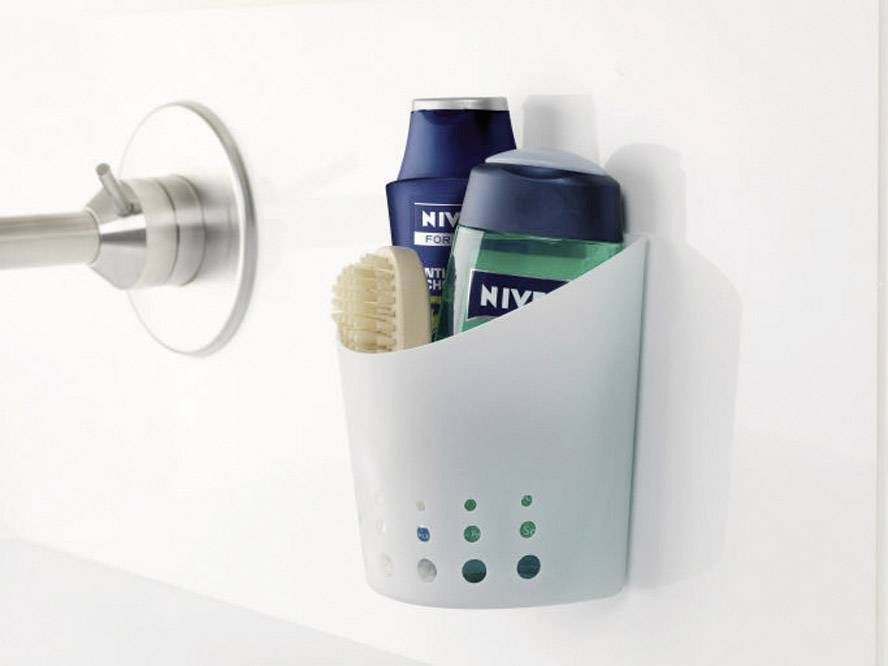 Deux produits Nivea et une brosse dans un panier de douche blanc, suspendus à un mur de salle de bain.