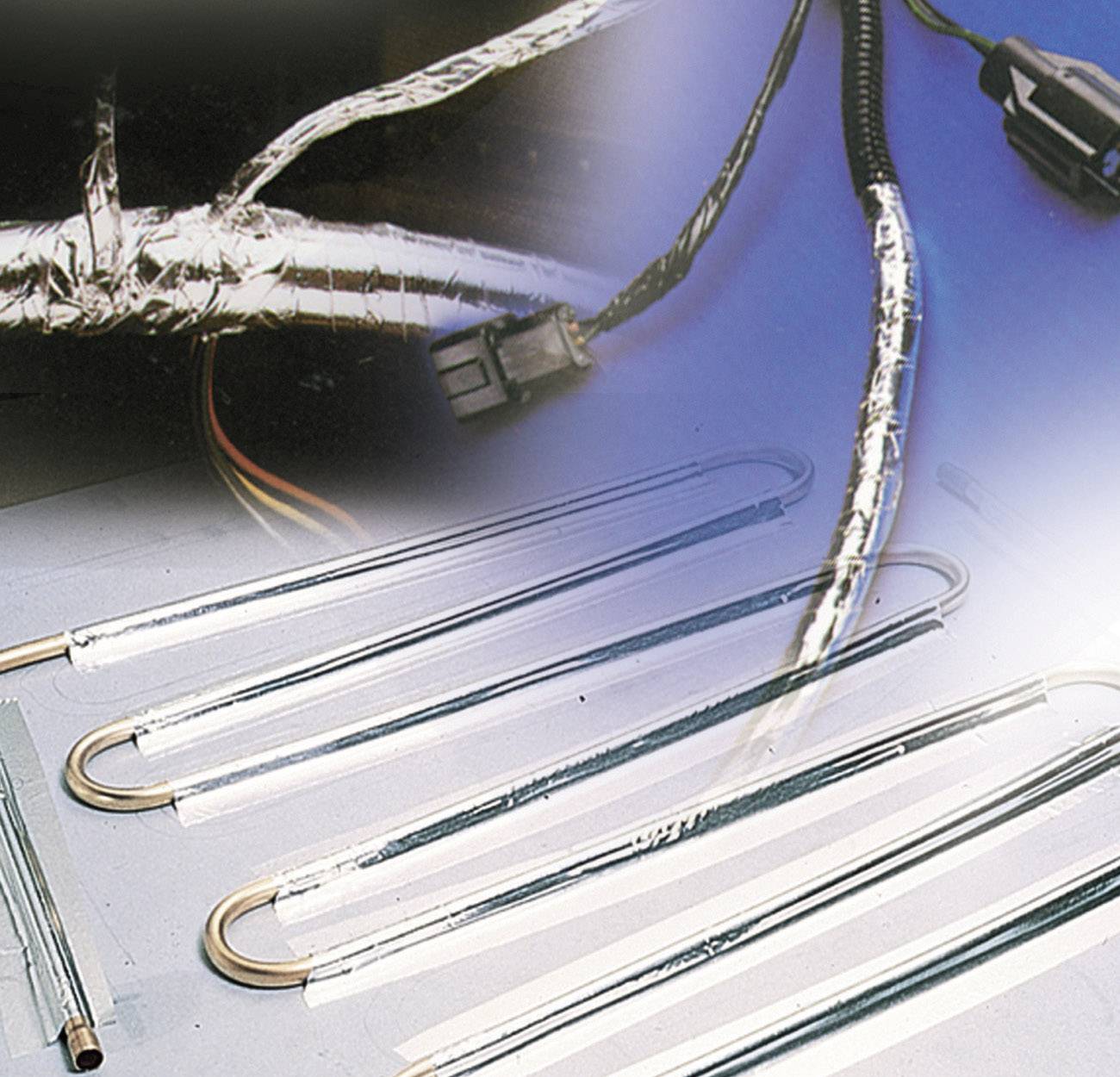 Plusieurs câbles chauffants munis de connecteurs, en partie enroulés de ruban isolant, sont posés sur une table. Une fiche est visible.