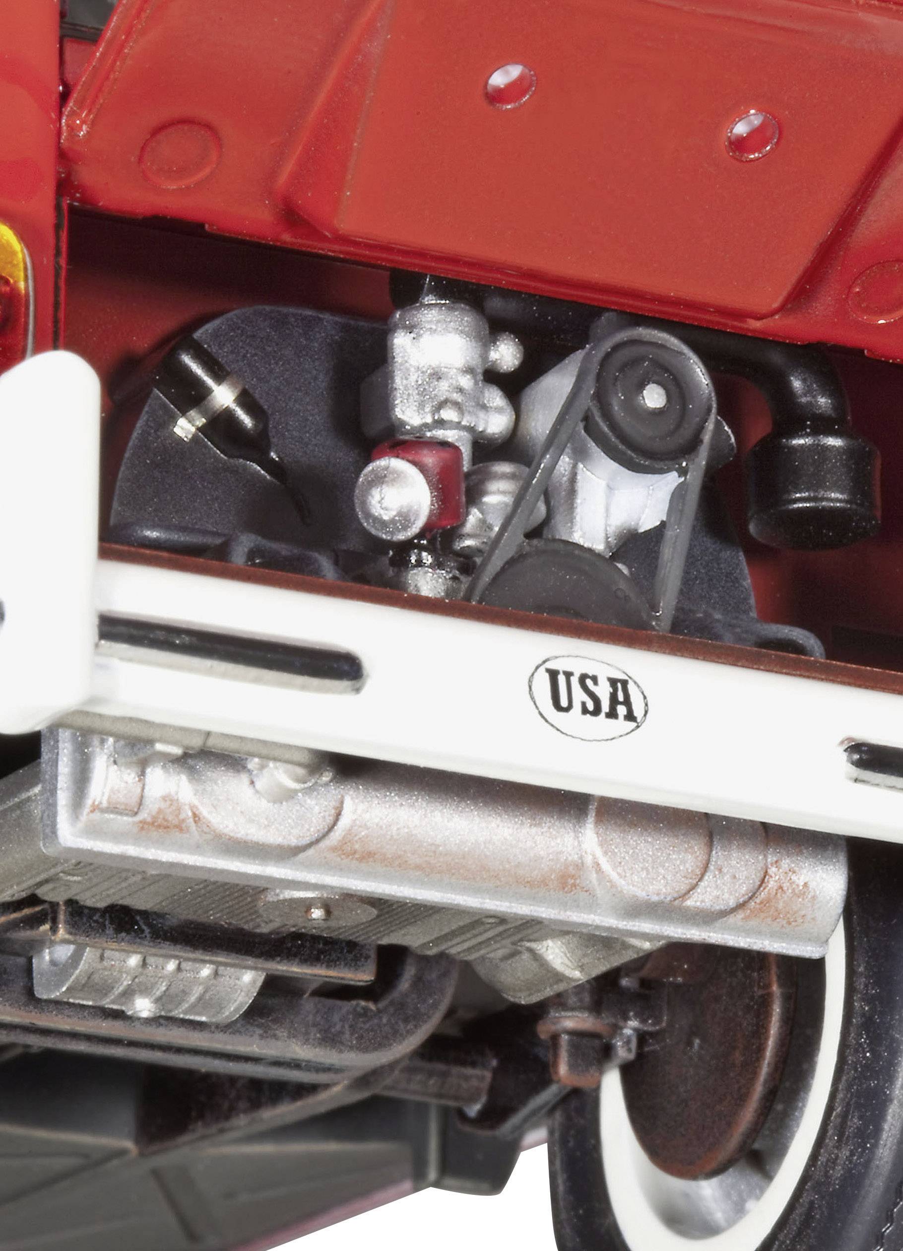 Gros plan du compartiment moteur d'une voiture vintage avec plaque « USA ». Des détails techniques tels que des courroies et des cylindres sont visibles. L'accent est mis sur la mécanique.