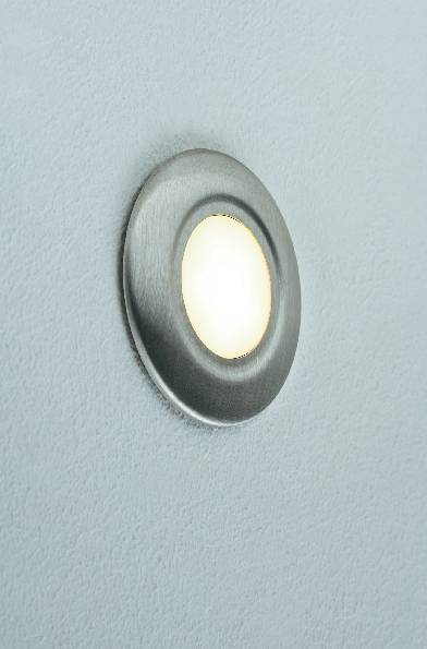Une ouverture d'objectif de caméra ronde et métallique sur une surface noire avec un fond bleu clair.