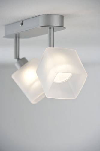 Plafonnier avec deux abat-jours hexagonaux blancs qui diffusent une lumière vive. Ils sont suspendus par des supports argentés.