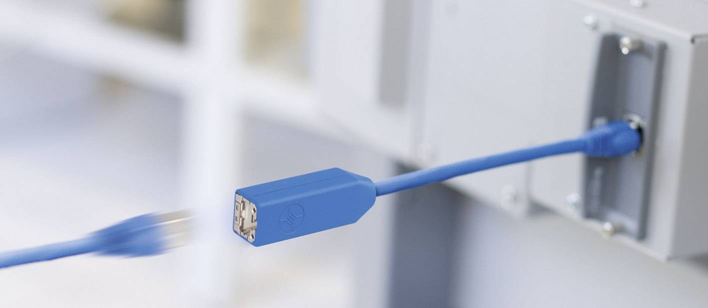 Un câble réseau bleu est branché dans un port, illustrant l'établissement d'une connexion dans un environnement technique.