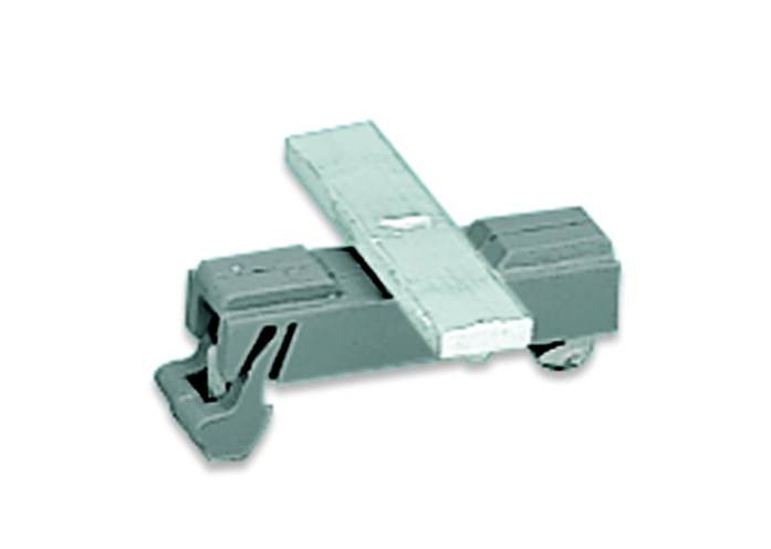 Un petit clip en plastique gris avec un levier métallique au centre, probablement un composant d'un mécanisme plus grand.