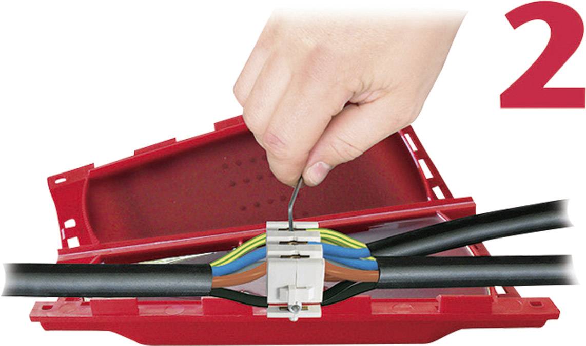 Une main connecte des fils colorés dans un bornier de connexion rouge. Le chiffre '2' est situé en haut à droite.