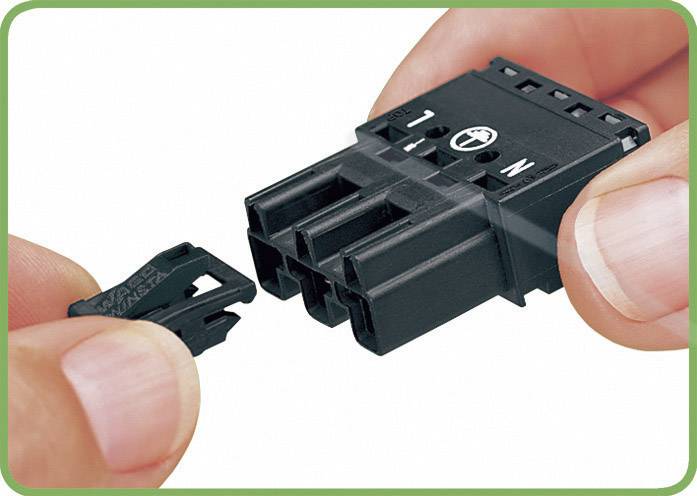 Deux mains connectent un connecteur électrique noir. La main gauche tient un petit clip, la main droite tient le connecteur principal.