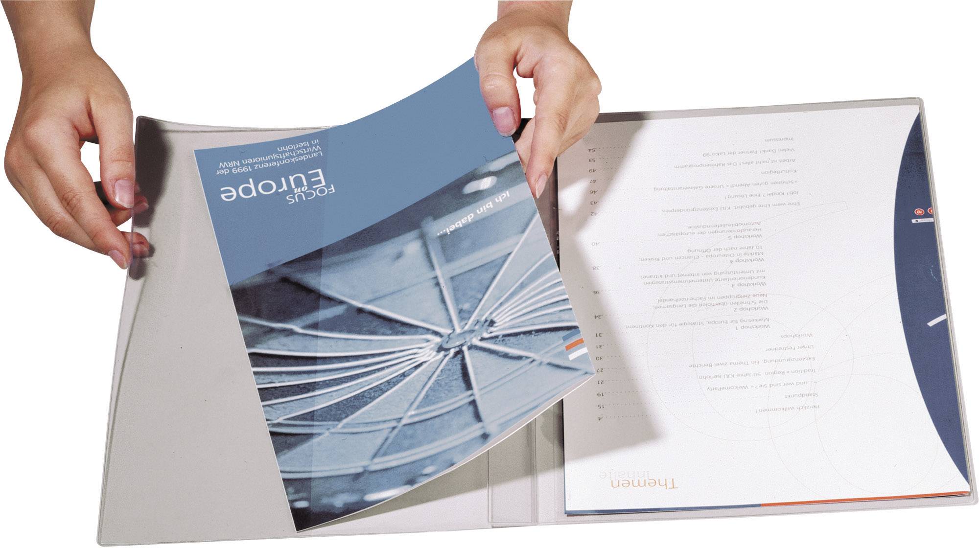 Deux mains ouvrent un dossier contenant des brochures bleues sur lesquelles est inscrit 'Focus Europe'. À l'intérieur, d'autres documents sont disposés.