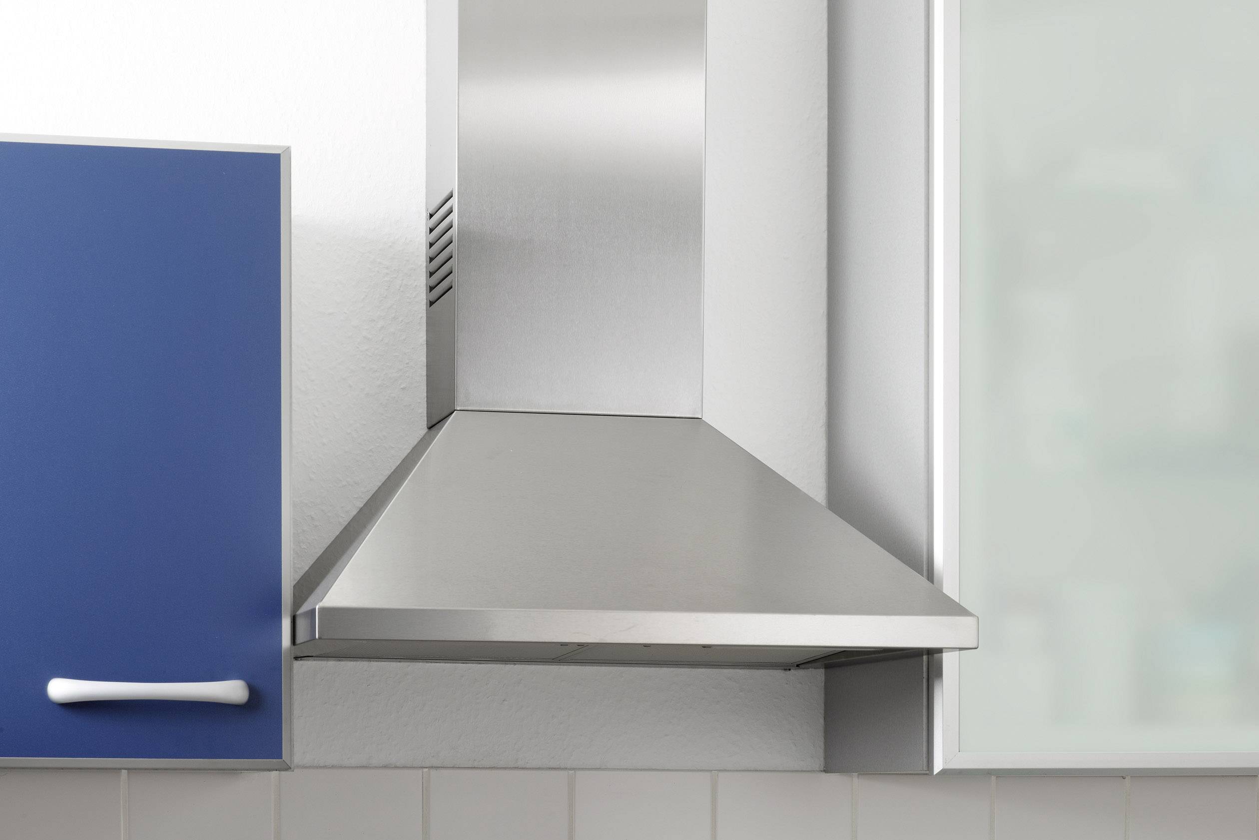 Une hotte aspirante moderne en acier inoxydable installée entre deux armoires de cuisine.