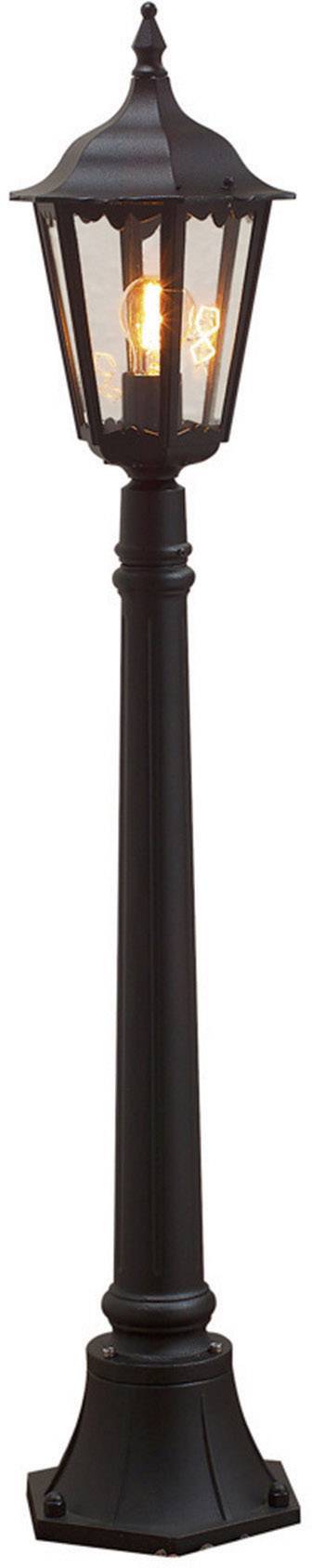 Une lanterne noire avec un abat-jour hexagonal et une ampoule brillante, reposant sur un socle.
