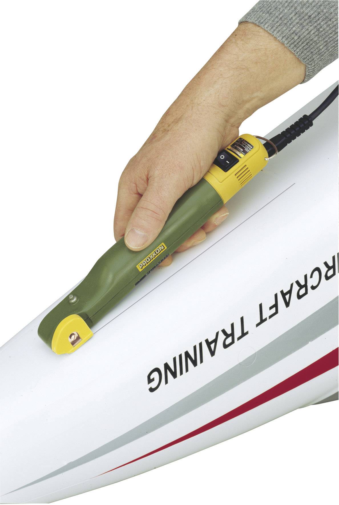 Une main tient un outil de construction aéronautique sur le fuselage d'un avion portant l'inscription 'Aircraft Training'.