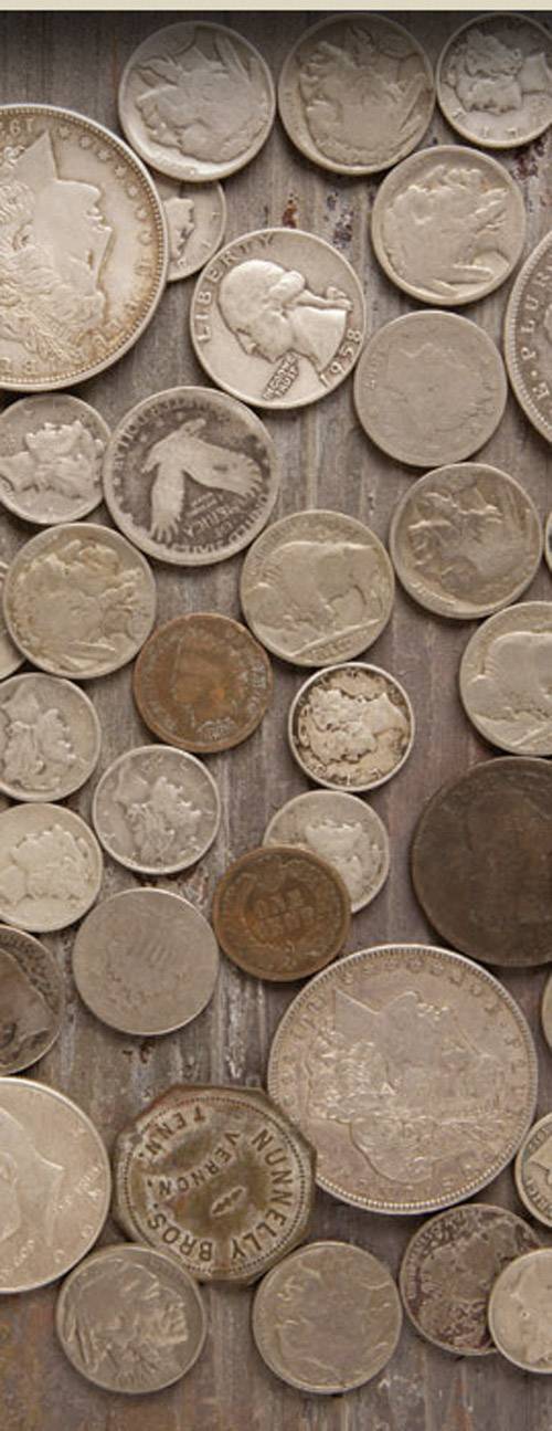 Une collection de pièces de monnaie anciennes de différentes tailles et couleurs est disposée de manière irrégulière sur une surface en bois.