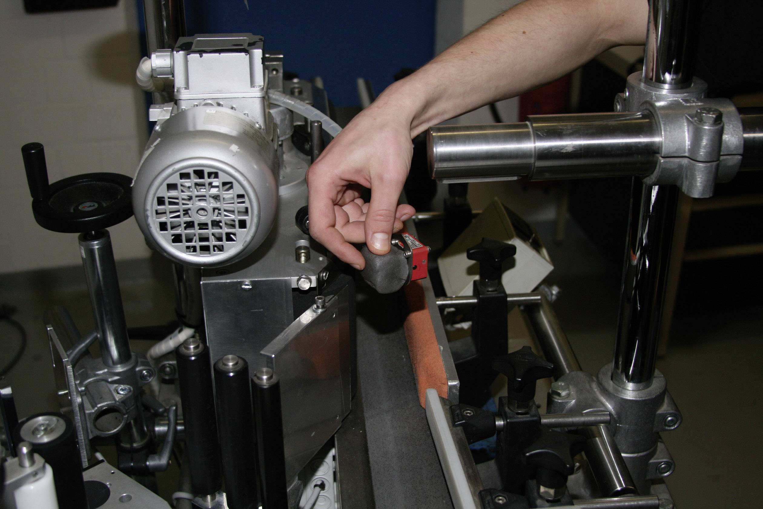 Un homme ajuste une machine industrielle avec une clé à molette, probablement pour un réglage précis d'un mécanisme.